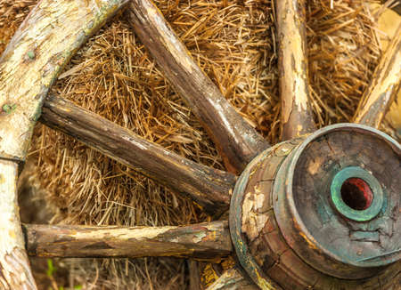 Old wagon wheel leaning against a straw bale.の写真素材