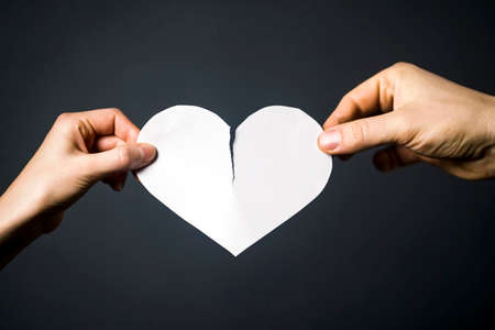 Two hands are tearing the white paper heart.の写真素材