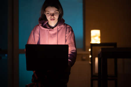 .The girl is surprised. She works on a laptop at home.の写真素材