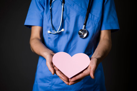 Young woman doctor, a cardiologist gently holds a pink heart in her hand.の写真素材