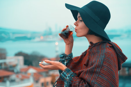A young girl in a poncho and a hat drinks fragrant delicious tea.の写真素材