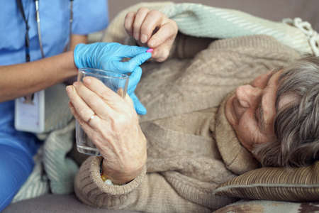 A young nurse is caring for an elderly 80-year-old woman at home.の写真素材