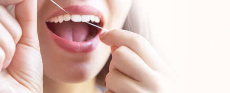Girl flosses her teeth in the morning.
