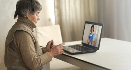 Aged woman talking using a video link with a female doctor.の写真素材