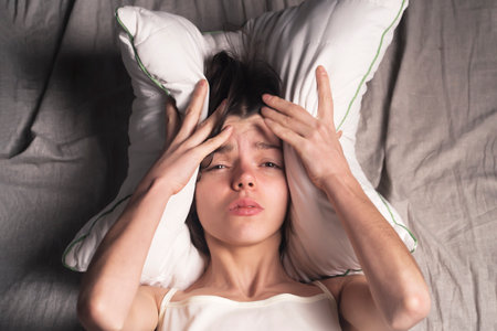 Young girl with a frightened expression wakes up from a nightmare in bed.の写真素材