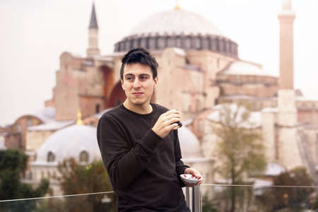 A young man drinks traditional Turkish tea.の写真素材