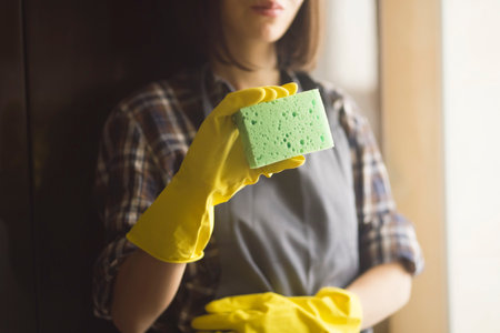 A woman in yellow rubber gloves does housework