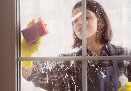 Woman washes the windows with a detergent.の写真素材