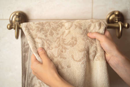 Girl is hanging clean towel on a holder.の写真素材