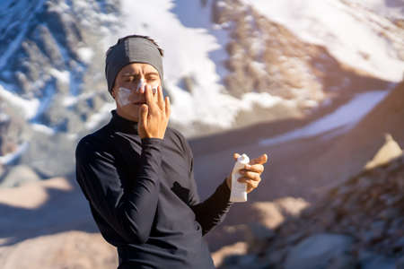 Traveler applies sunscreen cream on his face.の写真素材