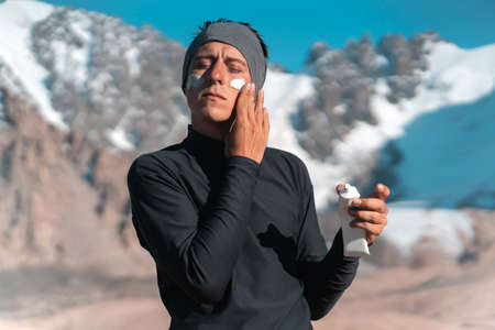 Traveler applies sunscreen cream on his face.の写真素材