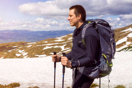 A young traveler with a backpack climbs the mountain,