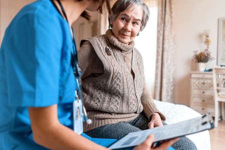 Young nurse is caring for an elderly 80-year-old woman at home,
