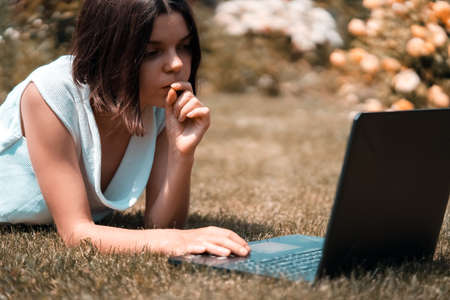 A young girl in a white dress is working on a laptop,の写真素材