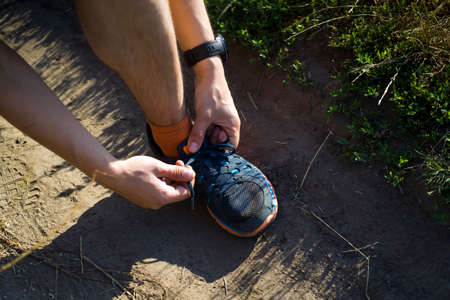 A young man ties the laces on his sneakers.の写真素材