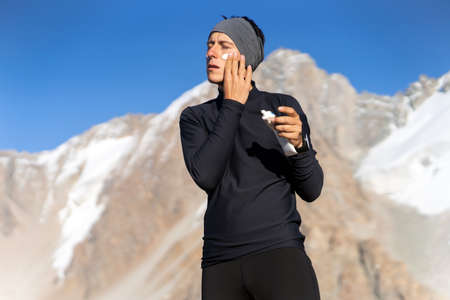 Traveler applies sunscreen cream on his face.