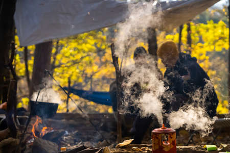 People are resting in the autumn park near the fire.