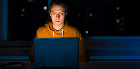 Man is working on a laptop at night.