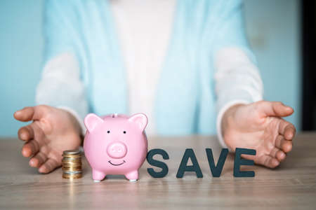 The girl puts her savings in a piggy bank.の写真素材