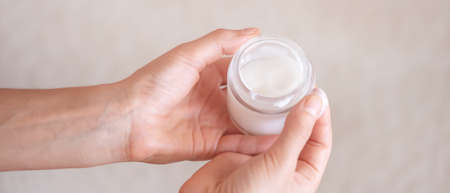 Female hands hold a jar of moisturizing cream.