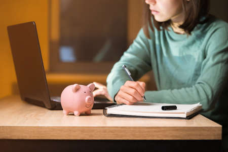 The girl puts her savings in a piggy bank.の写真素材