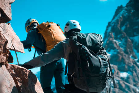Two men climbs to the top of the mountain.