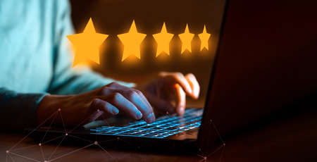 A person gives a five-star rating online using laptop.