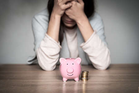 Sad girl with a piggy bank at home.の写真素材