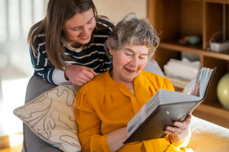 Old woman with her granddaughter look at family photos.の写真素材