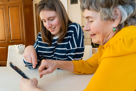 Girl helps her grandmother with mobile phone.の写真素材