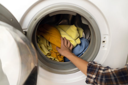 Woman puts bright clothes into a washing machine.の写真素材