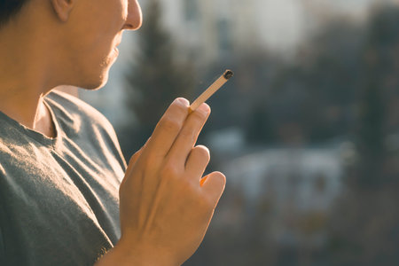 Young man is smoking cigarette near the window.