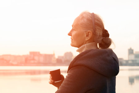 A woman, lady drinks a coffee and enjoys the sunset.の写真素材