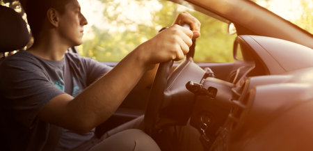 A man is driving a car, hands on the steering wheel closeup.