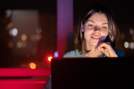 Young girl works on a laptop at night.の写真素材