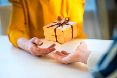 Female hands hold and give a nice packed gift.の写真素材