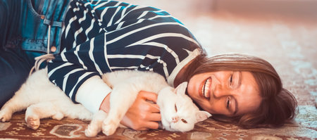 Funny girl hugs her white fluffy cat at home.の写真素材