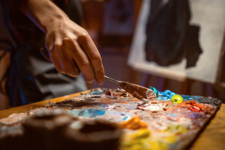 .Female artist Working on oil painting. In her hands are brushes and a palette. She paints a picture in the mysterious atmosphere of her studio.の写真素材