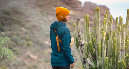 A young girl is trekking, hiking in the mountans among exotic plants and cacti.