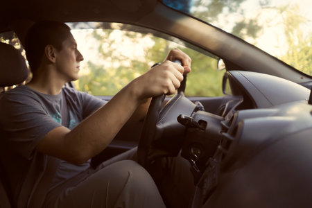 A man is driving a car, hands on the steering wheel closeup.