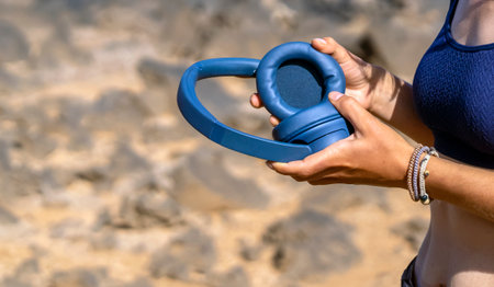 A girl with a wireless headphones, is listening music outdoors.の写真素材