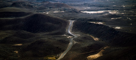 A road among volcanoes, mountains and black desert land in the national park.