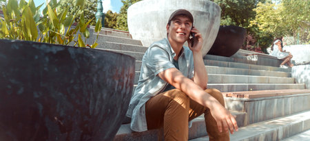 A young happy man talks, communicates on a smart phone outdoors.
