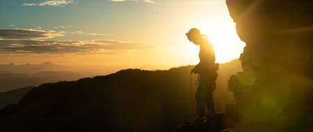 Young girl is preparing for training on the rocks sunset, in the mountains and puts a helmetの写真素材