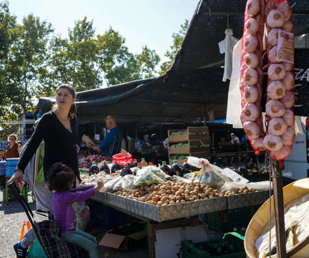A middle age woman s with her little girl in a walnuts stand in a street market in Madrid, Spain. September, 2017.のeditorial素材