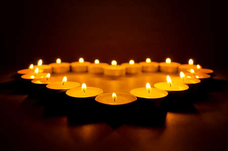 Burning candles in the shape of heart close up in the dark.の写真素材