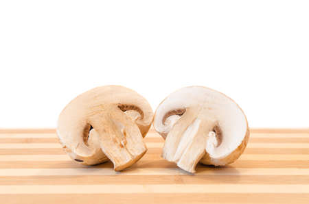 Halved mushroom lies on chopping board close-up isolated on white background.の写真素材