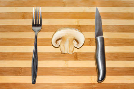 Sliced ââmushroom with knife and fork on wooden table striped background.の写真素材