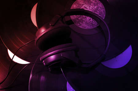 Big headphones on the background of vinyl LPs in colored raysの写真素材