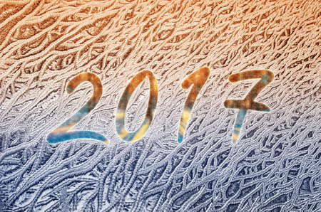 New year 2017 written on a frozen glass at sunset background
